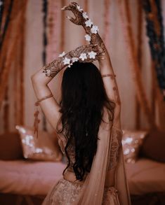 a woman with long hair wearing a bridal dress and holding her hands up in the air