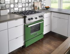 a green stove top oven sitting inside of a kitchen next to white cabinets and drawers