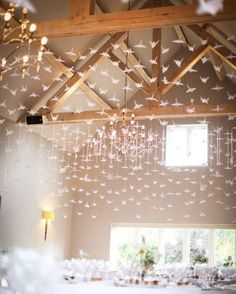 a chandelier hanging from the ceiling in a room with white tables and chairs