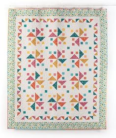 a quilted wall hanging on the side of a white wall with an orange, green and