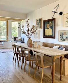 a dining room table with chairs and pictures on the wall above it, in front of a couch