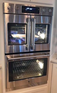 two double ovens are built into each other in this kitchen with white cabinets and stainless steel appliances