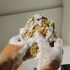 a person holding up a doughnut with icing on it