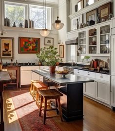 a large kitchen with white cabinets and wooden floors is pictured in this image, there are two stools at the center of the island