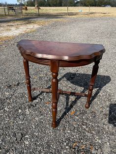 a wooden table sitting in the middle of a gravel road next to a horse pasture