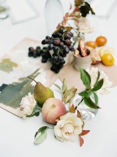 flowers and fruit are arranged on a table