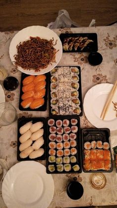 a table topped with plates and bowls filled with sushi next to chopsticks