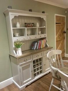 a dining room table and chairs in front of a hutch with books on it