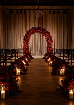 the aisle is decorated with candles and flowers for an elegant wedding ceremony in red tones