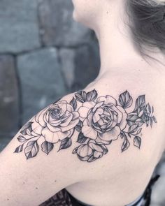 a woman's shoulder with flowers and leaves tattooed on her arm, in black ink