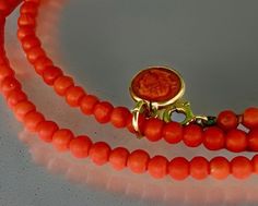 This is a dainty coral cameo pendant on coral bead necklace. It comes from the Italian workshops and depicts a Greek hero on one side and a classic building on the other.  the small circular piece is 1cm in diameter and is set in a gold tone metal, not marked and is highly likely to be gold.  This pendant isn't old, but in keeping with coral cameos carved in Torre del Greco near Naples. In this famous location during the 19th century are highly prized for their exquisite craftsmanship and historical significance. These intricate pieces often feature intricate portraits and mythological scenes. They represent not only the skill of the artisans but also the cultural and artistic trends of the era.  Due to their rarity and beauty, these cameos are valuable collector's items and no two cameos Coral Double Strand Jewelry Gift, Coral Double Strand Jewelry As Gift, Coral Double Strand Jewelry For Gifts, Elegant Coral Necklace With Lobster Clasp, Elegant Coral Pendant Necklace, Classic Coral Jewelry Gift, Classic Coral Jewelry As Gift, Elegant Red Coral Pendant Jewelry, Greek Heroes