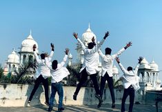 a group of men jumping in the air with their hands up and one man holding his arms out