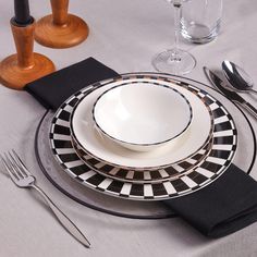 a table set with black and white plates, silverware and utensils on it