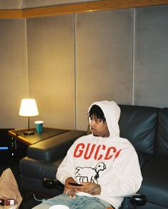 a man sitting in a chair wearing a gucci hoodie