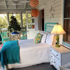 a bed sitting on top of a wooden floor next to a table with a lamp