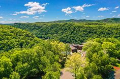 an aerial view of a wooded area with mountains in the background