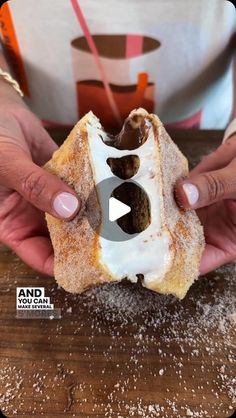 a person holding a doughnut with white frosting and chocolate on it in their hands