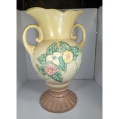 a yellow vase with flowers painted on it