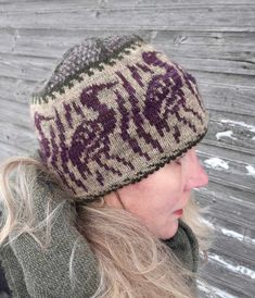 a woman with blonde hair wearing a knitted beanie hat in front of a wooden wall