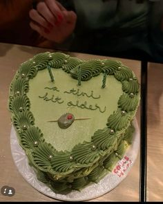 a green heart shaped cake with writing on it