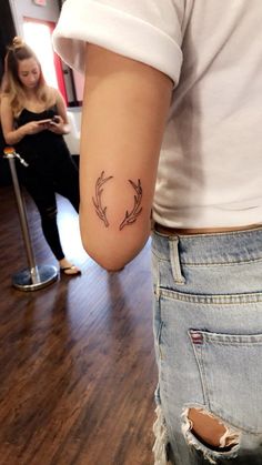 a woman with a tattoo on her arm is standing in front of a mirror and looking at her phone