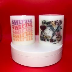 two candles sitting on top of a white stand next to each other with pictures on them