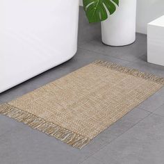 a rug with fringes on the floor next to a bathtub