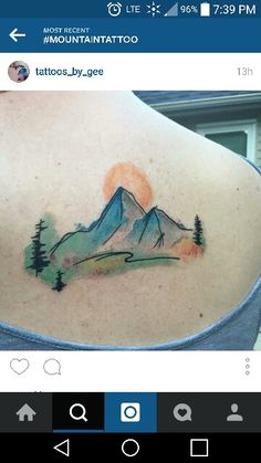 the back of a woman's shoulder with a mountain tattoo on it