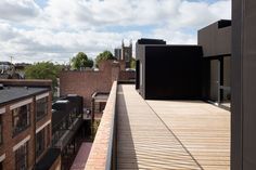 a balcony with wooden floors and brick buildings on the other side that overlooks cityscape