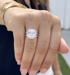 a close up of a person's hand with a diamond ring on their finger