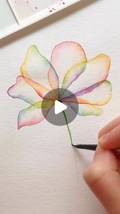 someone is drawing a flower with watercolors on paper and using a pencil to draw it