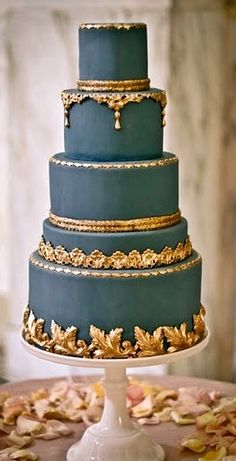 a blue wedding cake with gold decorations on top