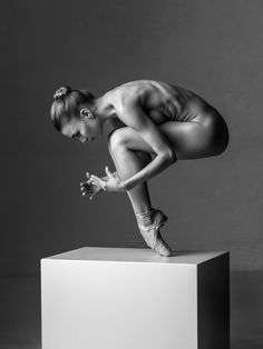 a naked woman standing on top of a white box