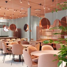 a restaurant with tables and chairs, hanging lights and plants on the wall in front of them