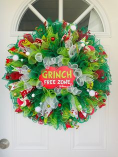 a christmas wreath with the words grin free zone hanging on a white front door in front of a window