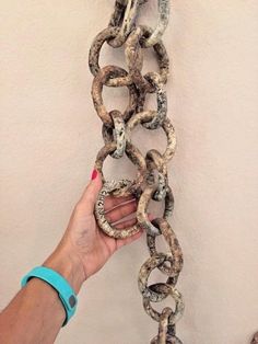 a hand holding a chain that is hanging on the wall