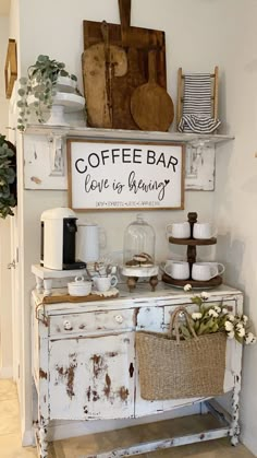 an old white cabinet with coffee bar sign above it and flowers on the top shelf