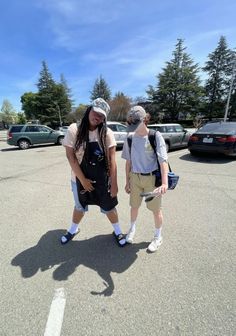 two people standing in the middle of a parking lot with cars behind them and one person wearing a visor