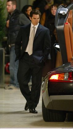 a man in a suit and tie standing next to a car