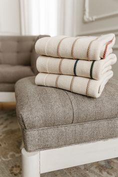 four folded towels sitting on top of a bench in front of a couch and chair