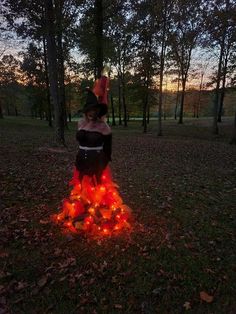 a woman dressed up as a witch standing in the woods with her hands on her hips