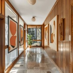 a long hallway with wood paneling and artwork on the walls