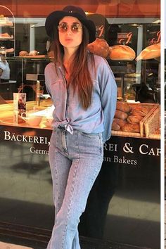 a woman standing in front of a bakery window with her hands on her hips and looking at the camera