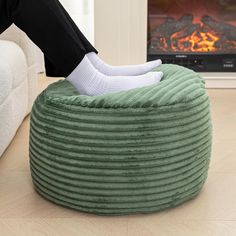 a person sitting on a bean bag chair in front of a fireplace with their feet propped up