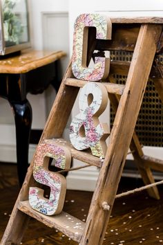 the letters are made out of toilet paper and placed on top of a wooden ladder