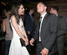 a man and woman standing next to each other in front of people at a party