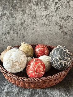 a wicker basket filled with ceramic ornaments on top of a wooden table next to a gray wall