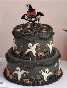 a three tiered cake decorated with black icing and halloween decorations, on top of a table