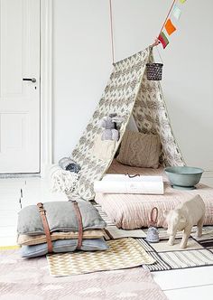 a teepee tent sitting on top of a floor next to pillows