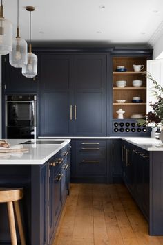 Blue cabinets with textured brass fittings, wooden bar stools around a kitchen island with white marble work tops and textured glass pendant lights Hacienda Kitchen, Dark Blue Kitchens, Bespoke Kitchen Design, Shaker Style Kitchens, Shaker Kitchen, Kitchen Worktop, Residential Interior Design, Bespoke Kitchens